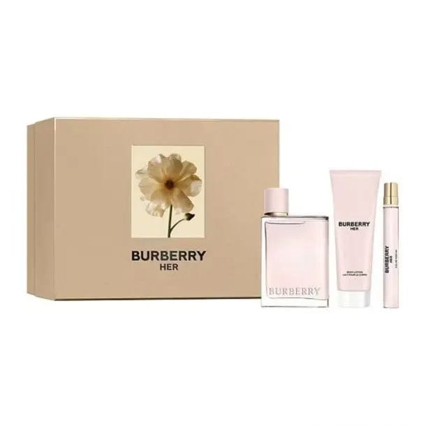 The Burberry Her gift set with its elegant, light-gold box featuring a floral design. The perfume bottle, body lotion, and travel spray are positioned in front of packaging, highlighting the complete and sophisticated presentation.