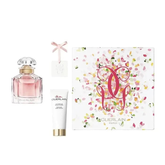 The Mon Guerlain 2-piece gift set, displaying the quadrilobe Eau de Parfum bottle, the perfumed body lotion, and the white gift box decorated with colorful petals.