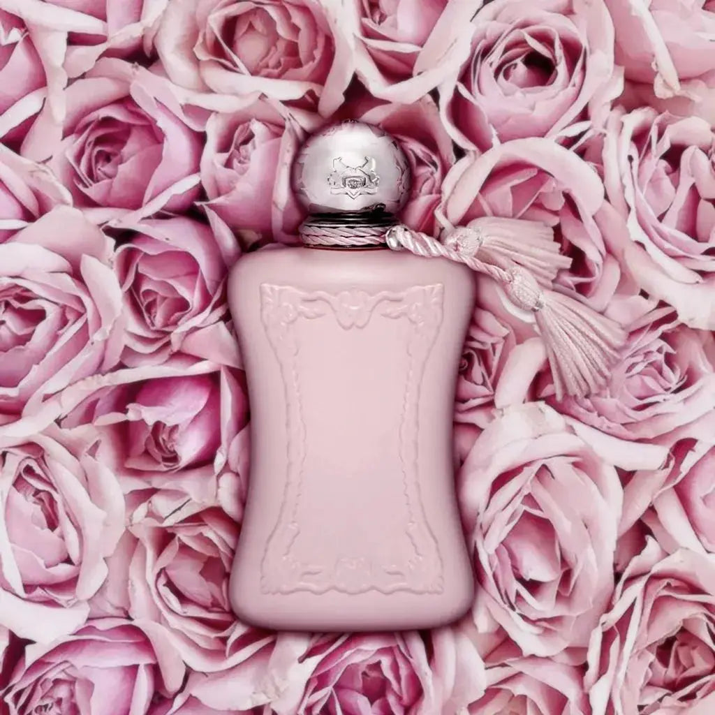 A professional product shot of the Parfums De Marly Delina perfume bottle. The image highlights the bottle's elegant, frosted pink glass, the decorative tassel, and the brand's iconic emblem.