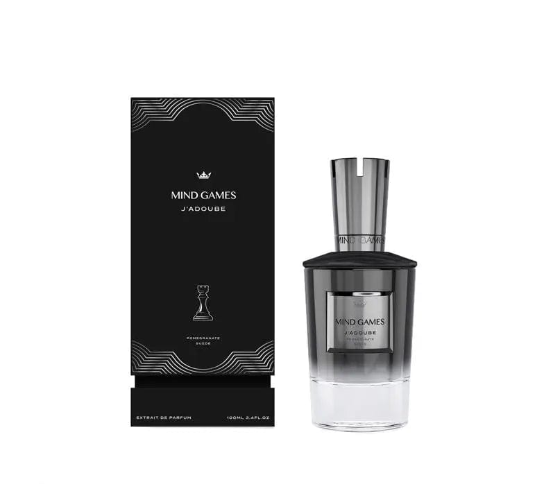 The Mind Games J'adoube perfume bottle, with its ombre gray and clear glass, displayed next to its sleek, black and silver patterned box. The image showcases the complete, luxurious presentation of the product.