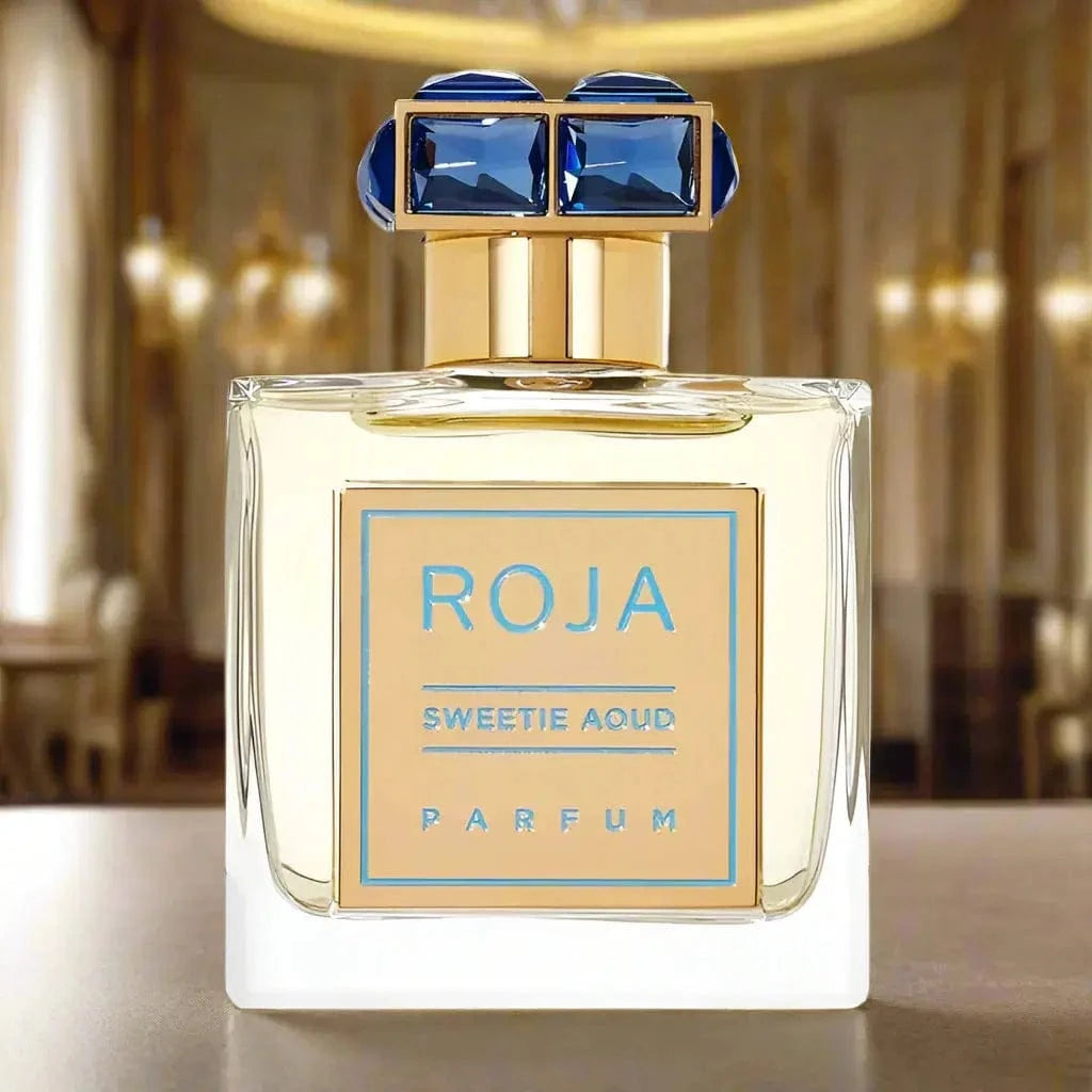 A clear product shot of the Sweetie Aoud by Roja Parfums 1.7 oz bottle, highlighting the script font and the brilliant blue jeweled cap on a white background.