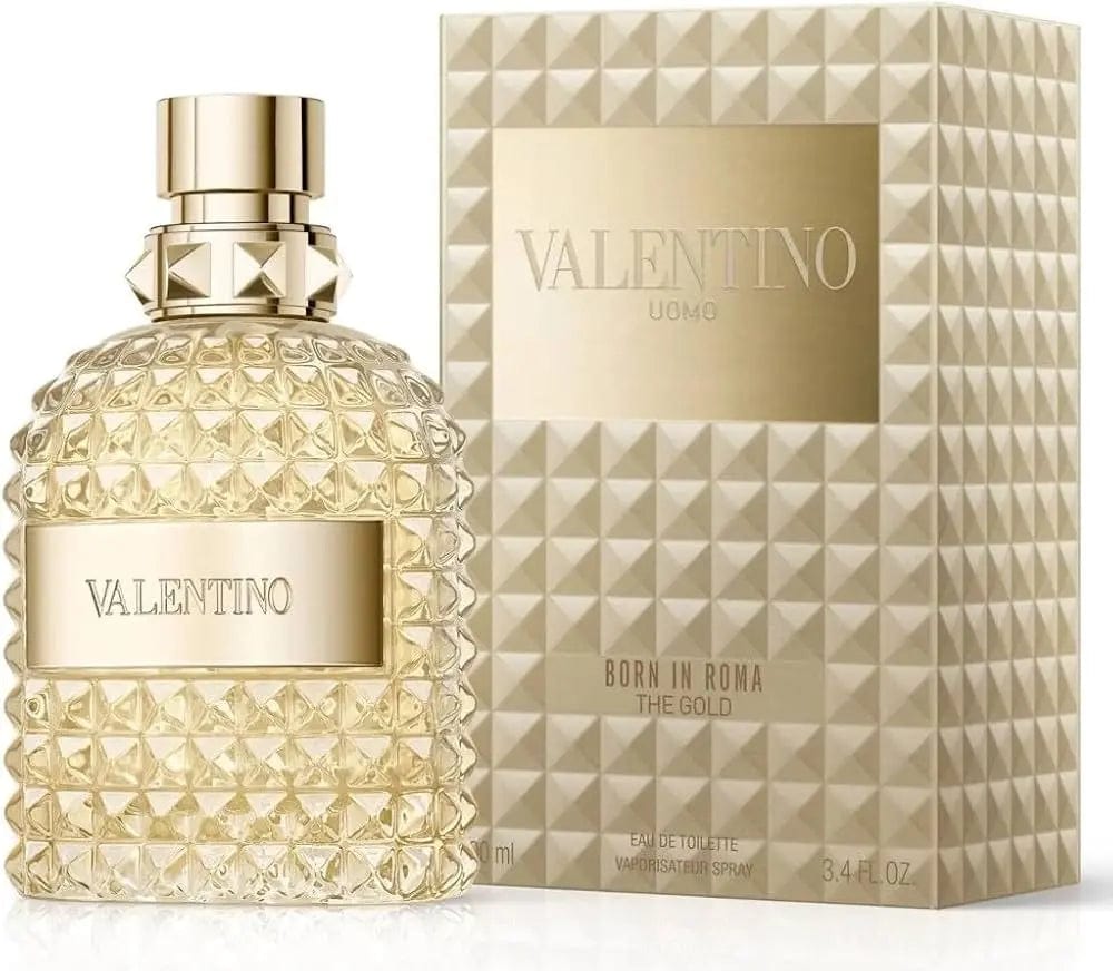 The Valentino Uomo Born in Roma The Gold 3.4 oz bottle displayed next to its matching gold-studded presentation box.