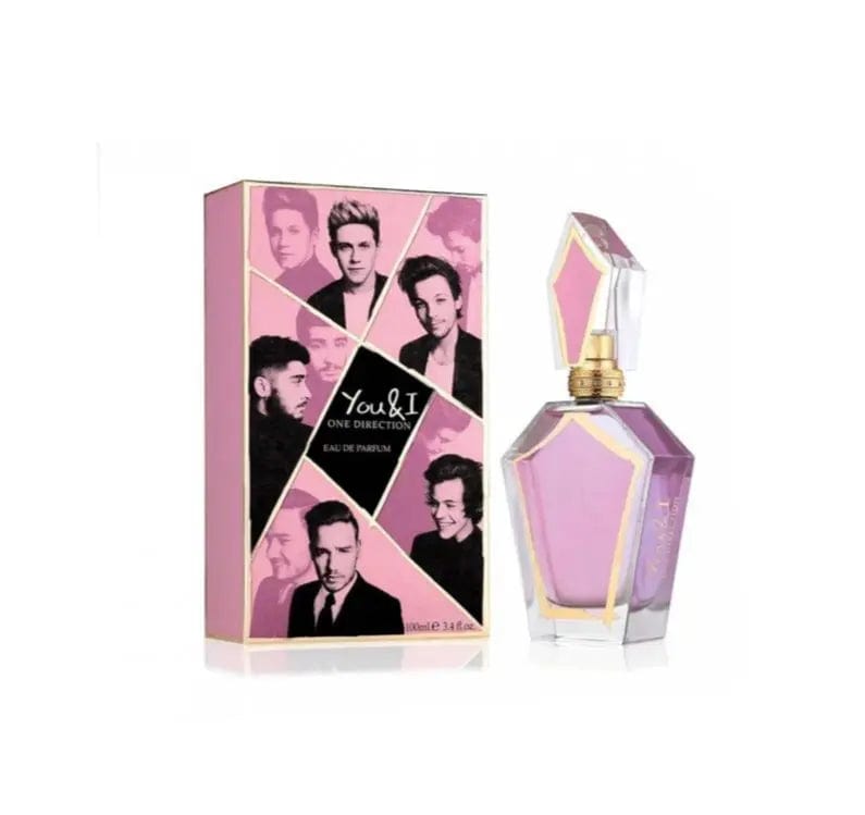 An elegant, multi-faceted glass bottle of You &amp; I One Direction Eau de Parfum spray with pink liquid and a geometric stopper, displayed next to its matching pink and gold box featuring images of the One Direction band members.